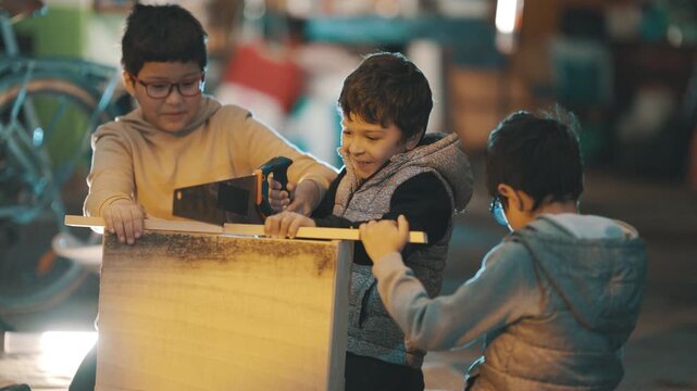 Young boys learning woodworking skills together in garage workshop