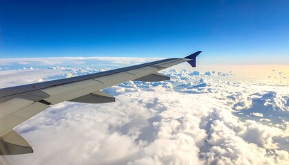 Obraz premium Airplane Wing Soaring Above the Clouds in a Bright Blue Sky.