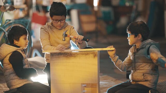 Three young boys building a wooden box together in a workshop