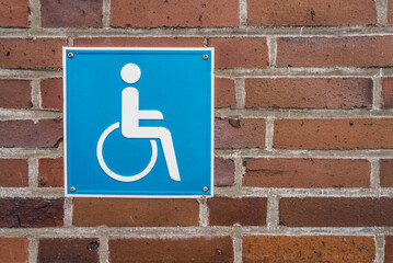 Handicaped parking sign on a brick wall.
