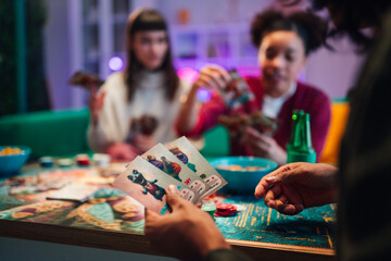 Fototapeta premium Friends enjoying casual games at home, having fun playing card game during social gathering evening