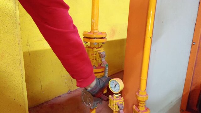 Opening the main gas valve of an industrial drying boiler for fire cabinet production. A technician starts the gas supply for a large industrial boiler to dry metal fire cabinets after chemical cleani