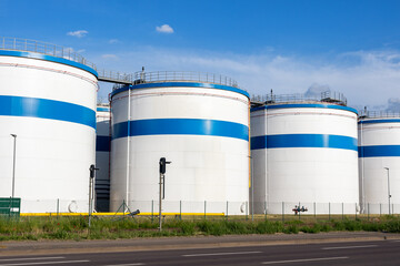 Row many large industrial fuel storage white tanks clear blue sky background on sunny day. Oil...