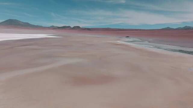 Aerial view of pink flamingos gathered on a high-altitude lagoon in Bolivia&rsquo;s Sud L&iacute;pez region, surrounded by volcanic landscapes and the Andes.