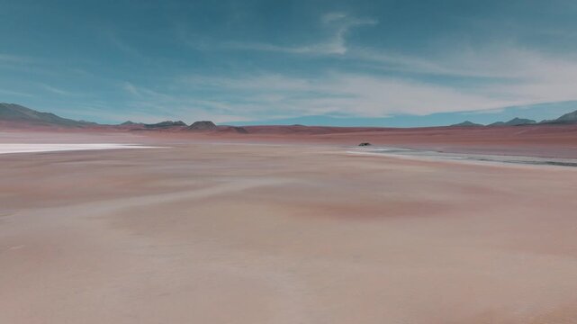 Aerial view of pink flamingos gathered on a high-altitude lagoon in Bolivia&rsquo;s Sud L&iacute;pez region, surrounded by volcanic landscapes and the Andes.