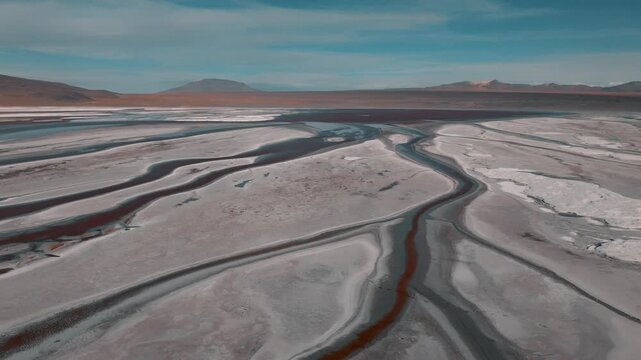 Aerial view of a salt lake in the Bolivian Altiplano, with pale mineral water and reflective surface. Minimalist landscape with soft tones and remote atmosphere.