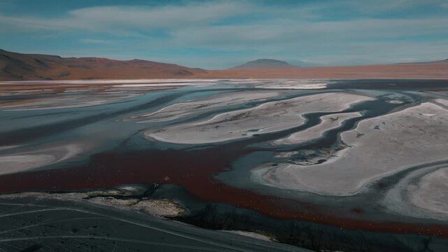 Aerial view of a salt lake in the Bolivian Altiplano, with pale mineral water and reflective surface. Minimalist landscape with soft tones and remote atmosphere.