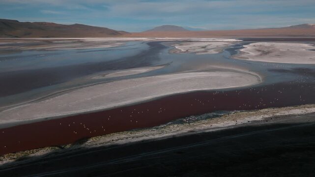 Aerial view of a salt lake in the Bolivian Altiplano, with pale mineral water and reflective surface. Minimalist landscape with soft tones and remote atmosphere.