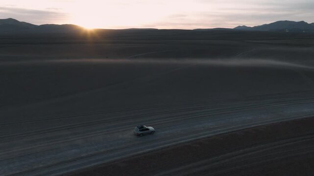 Aerial view of a 4x4 driving across the vast wilderness of Sud L&iacute;pez, Bolivia. Volcanic mountains and high-altitude deserts stretch to the horizon.