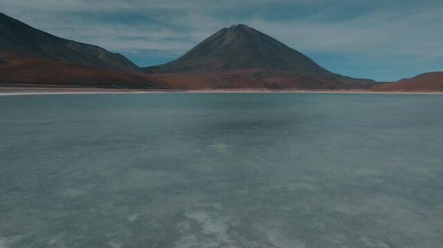 Aerial view of Laguna Verde in Bolivia, vibrant green mineral lake in the Andes Altiplano. Colorful water contrasting with desert landscape under clear sky.