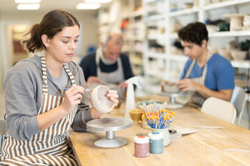 Young woman pottery workshop workers sculpt from raw clay