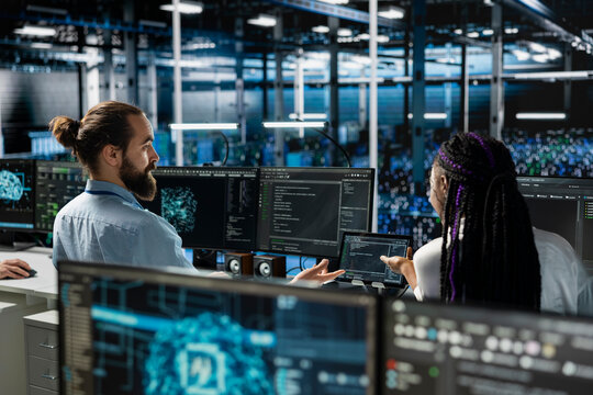 Data center team leader and intern working together on AI databases. Server room manager and trainee using deep learning artificial intelligence on PC to do algorithms improvements