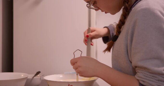 Culinary Craft: A young woman diligently whisks ingredients in a mixing bowl. This scene captures the essence of home cooking and the joy of creating a delicious treat.