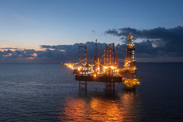 Aerial view of offshore jack up rig and offshore platform during sunset for oil and gas exploration...
