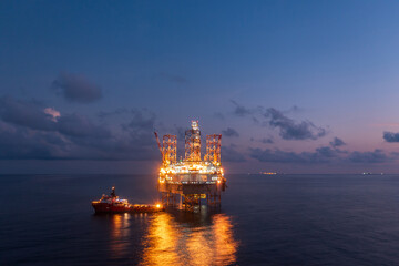 Aerial view of offshore jack up rig and offshore platform during sunset for oil and gas exploration...