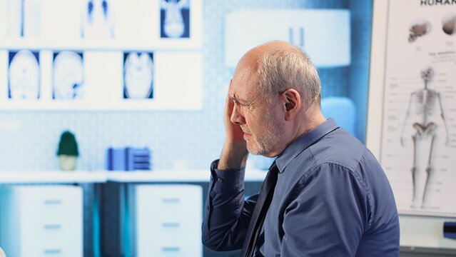 Female doctor in a clinic evaluates a man cognitive function and reflex, using a pen light to test pupil response and focus after a head trauma. Healthcare provider. Camera B.
