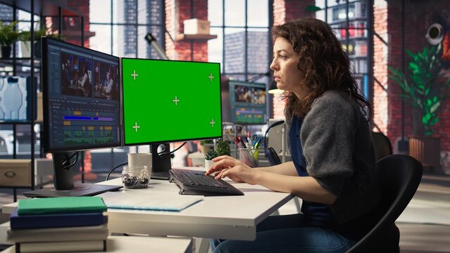 Woman video creator edits a multimedia project next to chroma key at agency office, using professional tech tools and editing software to manage timeline editing and video production. Camera A.