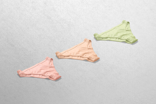 Blank colored women bikini underwear mockup, side view, 3d rendering. Empty pink, orange and green bottom cheeky slips mock up, grey background. Clear tankini beachwear briefs template.