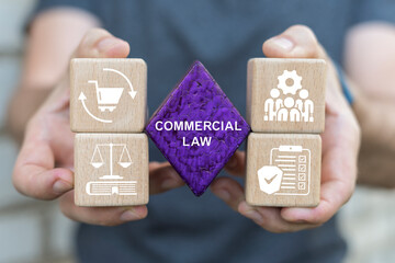 Concept of commercial law. Person holding blocks with icons sees the text COMMERCIAL LAW.