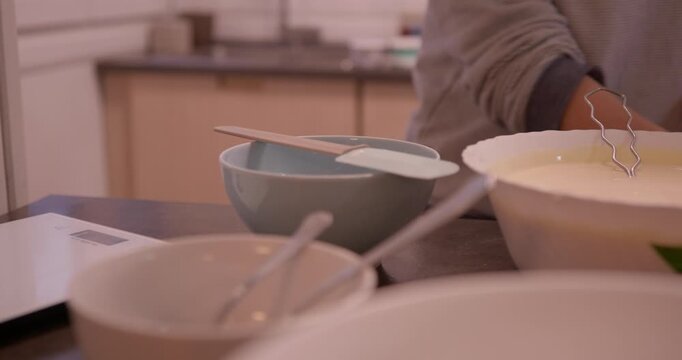 Preparing culinary delights: A close-up shot of a person mixing ingredients in kitchen, a symphony of culinary tools. Capturing the art of mixing, whisks and bowls, and spatula.