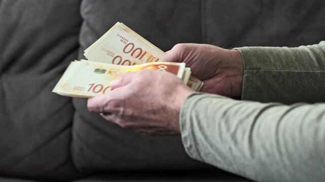 Man Hands Counting Stack of One Hundred Israeli New Shekel Banknotes