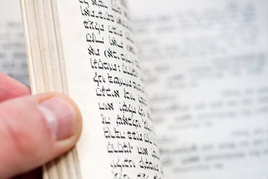 Hand Turning Page of Antique Hebrew Prayer Book