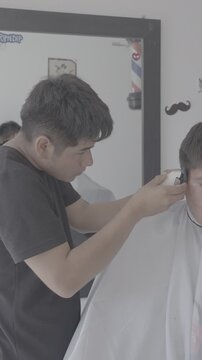 Professional barber giving a haircut with an electric clipper