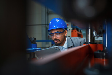 An industrial engineer conducts machine inspection in a factory, ensuring quality control and...