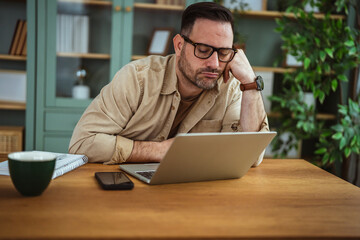 Exhausted man feeling burnout and napping at home office desk