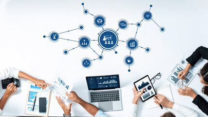 A dynamic business meeting scene featuring a collaborative team analyzing data graphics on digital...