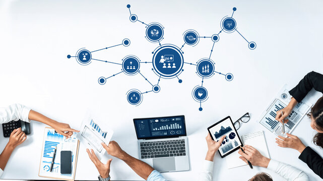 A dynamic business meeting scene featuring a collaborative team analyzing data graphics on digital devices, showcasing a modern workspace with innovative technology. Amity