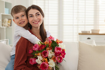 Mother's Day. Woman with her son and bouquet of flowers at home, space for text