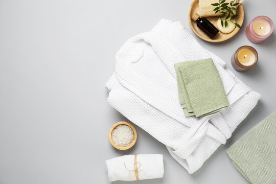 Flat lay composition with bathrobe and spa products on white background, space for text