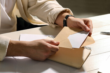 Naklejka premium Man opening envelope with letter at wooden table indoors, closeup