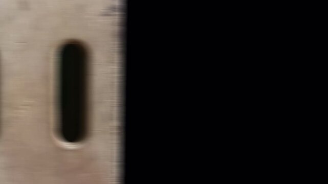 Close-up of a metal surface with two vertical slots, possibly part of a ventilation system or industrial machinery.