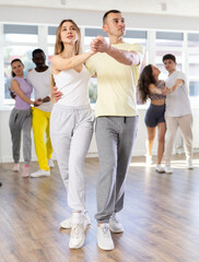 Obraz premium Couple of young guy and young woman dancing latin dances in studio