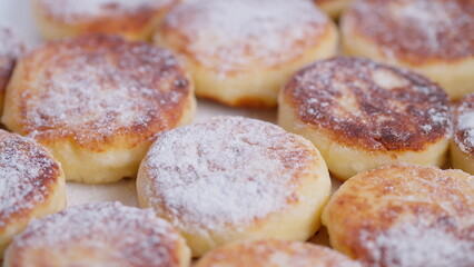 Freshly made golden pancakes topped with sugar in morning light, Closeup of soft curd center pancakes garnished with powdered sugar on rustic surface during dawn