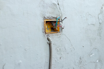 disassembled electrical outlet socket against an exterior wall