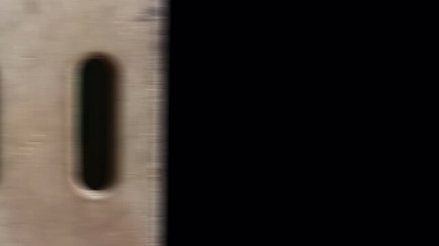 Close-up of a metal surface with two vertical slots, possibly part of a ventilation system or industrial machinery.