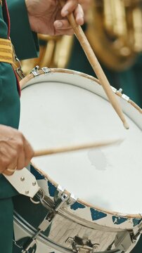 A wind instrument military parade - a person in green costume playing drums outdoors