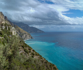 Fototapeta premium Amalfi Coast, Italy: Coastal cliffs and turquoise sea under cloudy sky