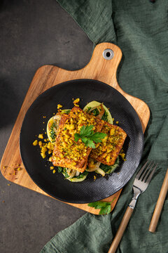 Top Down View of Roasted Tofu with Herb Crust and Saut&eacute;ed Greens on a Black Plate