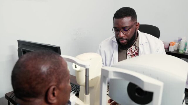 Optometrist examining a senior African man's eyes in a clinic with a non-contact tonometer (NCT)