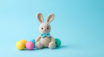 Fototapeta premium Knitted beige crochet bunny sitting among colorful easter eggs