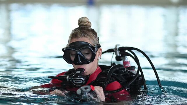 Woman preparing for scuba diving breathing from regulator and submerging in a swimming pool for a padi lesson