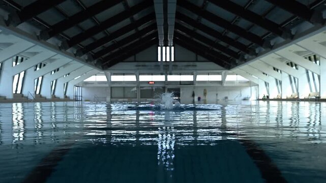 Professional swimmer training butterfly stroke in an indoor swimming pool, low angle water level view of her intense workout
