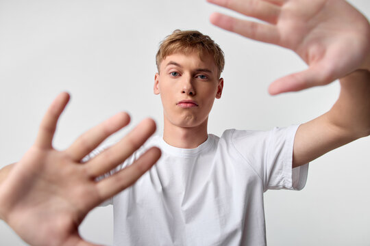 Hands reach toward the camera around a youth in a white t shirt, studio setting, dynamic perspective, bold framing, energetic moment, emphasis on gesture and proximity