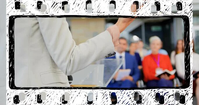 Presenter referencing notes on clear lectern, initiating gesturing, guiding conference audience