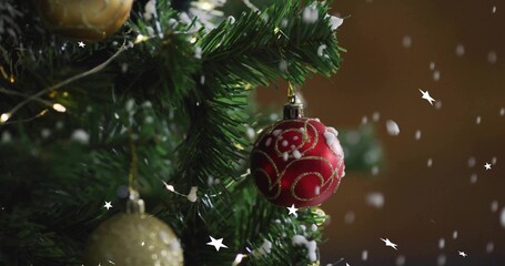 Hanging red bauble with gold swirls, white accents on fir branch with string lights, copy space