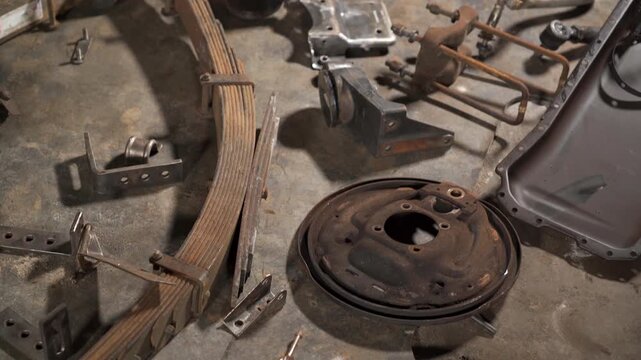 Various used car parts laying on the ground of a garage. 